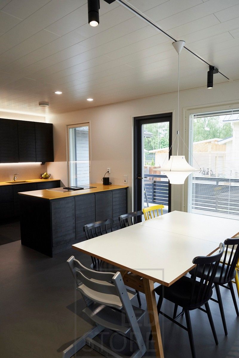 Directional, black led track lights illuminating the dining area. Small plafond lights on the island and led strips in the kitchen as indirect light. Ledstore.fi